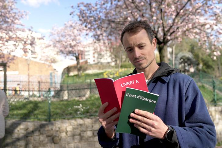Hugo Clément regarde un document sur lequel il est écrit Livret A